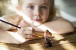 petite fille blonde au yeux bleu peint une pièce d'échecs cavalier